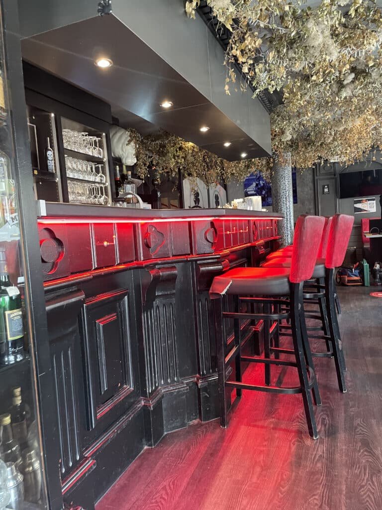 Espace bar à My Pub Rouen avec des tabourets rouges et une décoration intérieure élégante